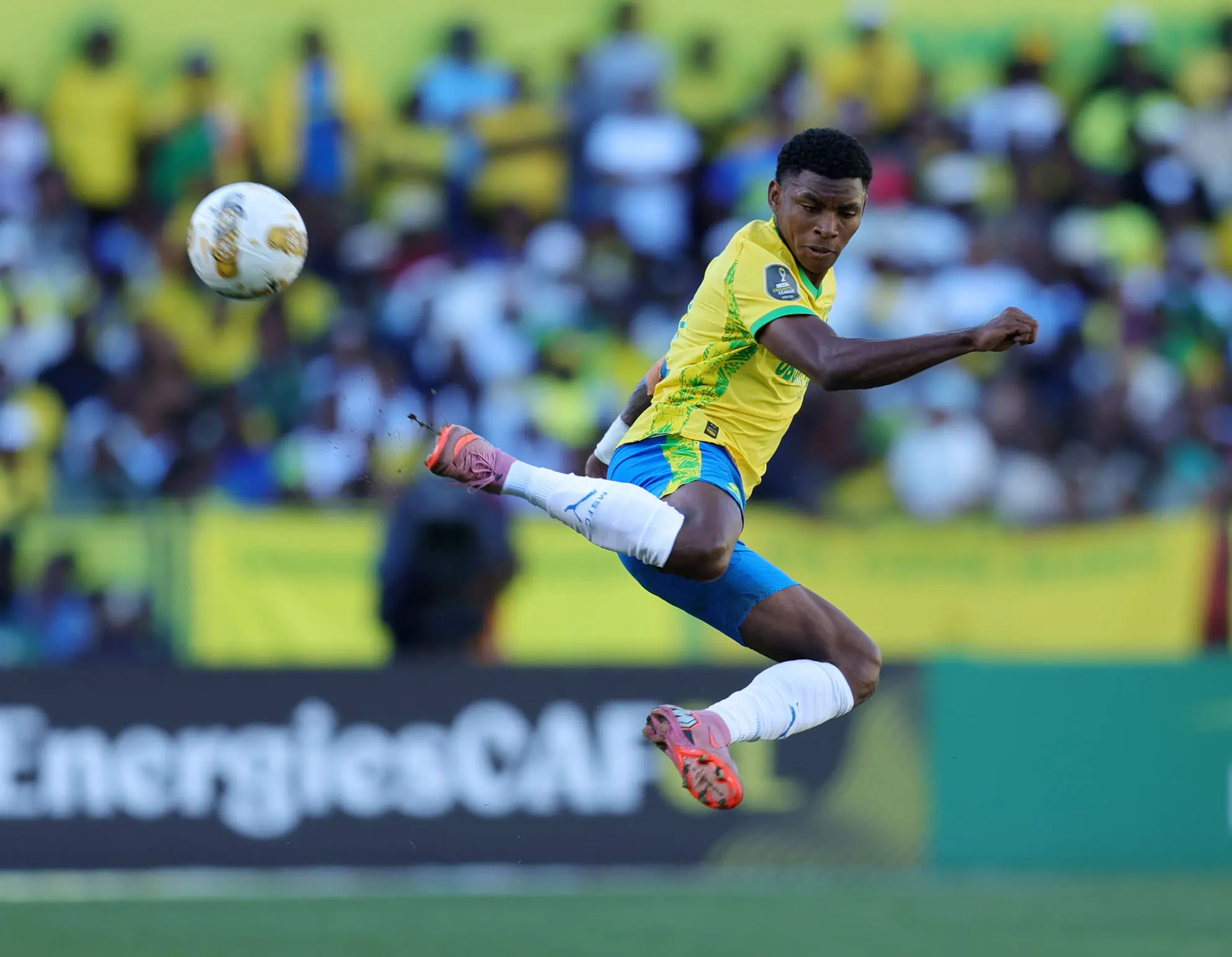A Mamelodi Sundowns player striking the ball in a match