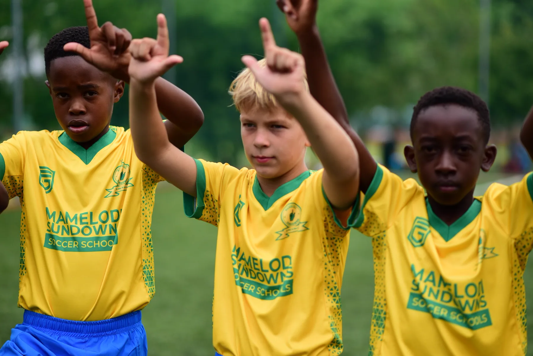 Young Mamelodi Sundowns Soccer Schools players raising the club hand sign