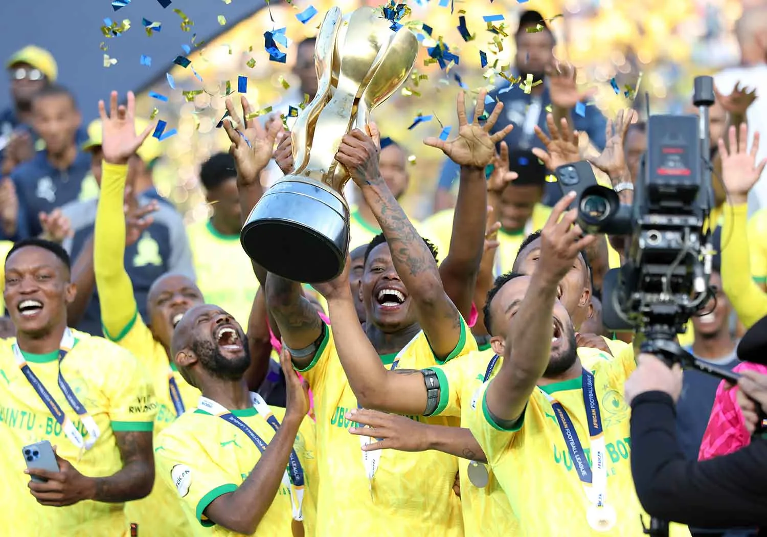 Mamelodi Sundowns players lifting the league trophy amid confetti