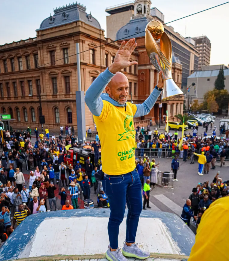 The Champions League trophy raised above a crowd on an open-top bus in central Pretoria