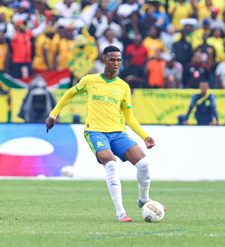 A Mamelodi Sundowns player on the pitch in front of a packed stand of supporters